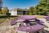 Charming outdoor setting with vibrant purple picnic tables against a backdrop of modern apartments and lush greenery.