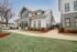 Charming modern home with sleek metal roof, large windows, and beautifully landscaped front yard.