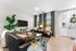 Bright and inviting living room with sleek black sofas, large windows, and tasteful decor, perfect for relaxation and entertaining.