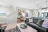 Chic and modern open-plan living room with stylish decor, featuring a comfortable sofa, elegant lighting, and a cozy wooden staircase leading upstairs.