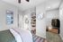Elegant bedroom with cozy bedding, spacious open closet, and chic decor including a large wall clock and artistic shelves.