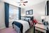 Charming bedroom with modern decor, featuring a cozy bed, stylish desk, and large window with vibrant blue curtains.