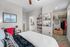 Elegant bedroom with modern decor, featuring a cozy bed, stylish shelving, and a walk-in closet with chic storage options.