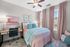 Charming bedroom with soft pink and teal accents, featuring elegant drapes, a cozy bed, and a stylish desk, perfect for a serene living experience.