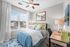 Bright bedroom featuring a comfy bed with stylish blue and white bedding, large window offering scenic views, and a sleek desk with decor.