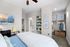 Charming bedroom featuring cozy bedding, stylish artwork, and open closet space with organized shelving for a modern touch.