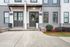Charming townhouse entrance with decorative wreath, modern facade, and lush greenery, creating a welcoming and stylish curb appeal.