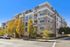Elegant beige brick apartment building with lush trees and clear blue skies, emphasizing urban elegance and modern living.