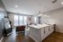 Modern open-concept living space featuring stylish kitchen with island, elegant pendant lights, and cozy sitting area by large windows.