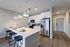 Modern kitchen with sleek white cabinetry, stainless steel appliances, and a chic island with barstools and pendant lighting.