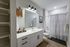 Modern bathroom showcasing sleek vanity with ample storage, stylish lighting, and elegant shower area with patterned curtain.