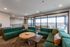 Modern living room with green sectional sofa, stylish decor, and large windows opening to a scenic balcony.