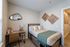 Cozy bedroom featuring a stylish bed with plush pillows, an elegant desk with modern decor, and artistic wall accents.