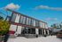 Modern leasing center with a sleek design, set against a vibrant blue sky and surrounded by lush greenery and landscaped gardens.