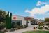 Modern leasing center with a sleek design, set against a vibrant blue sky and surrounded by lush greenery and landscaped gardens.