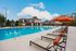 Luxurious apartment complex with a sparkling pool, modern clubhouse, and stylish sun loungers under vibrant umbrellas.