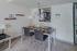 Elegant dining area with a modern table set for four, adjacent to a sleek kitchen view, creating a warm and inviting ambiance.