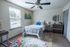 Bright and cozy bedroom featuring a comfortable bed, vibrant rug, and natural light from a large window.