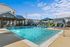 Inviting outdoor pool area with lounge chairs, modern cabana, and vibrant water features under a clear blue sky.