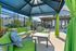 Inviting outdoor seating area with vibrant green cushions under a stylish cabana, perfect for relaxation near the pool.