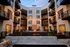 Charming apartment courtyard featuring modern balconies, cozy seating, and ambient string lights around a central fire pit.