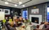 Cozy modern living room with a warm fireplace, stylish furniture, artistic decor, and a sleek chandelier.