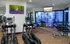 Modern apartment fitness center with state-of-the-art exercise equipment, vibrant artwork, and natural light from large glass windows.