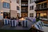 Cozy outdoor courtyard with striped seating around a warm fire pit, surrounded by elegant apartment balconies.