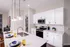 Sleek modern kitchen with white cabinetry, stainless steel appliances, and stylish pendant lighting over a marble island with seating.