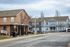 Charming suburban community with vibrant blue and beige townhouses, neatly maintained front yards, and a nearby covered bus stop for convenient public transport access.