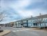Charming suburban townhouse community with vibrant blue and neutral exteriors, ample parking, and inviting curb appeal under a serene sky.