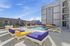 Vibrant apartment complex pool area featuring colorful lounge chairs and modern architecture under a clear blue sky.