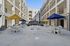 Modern apartment courtyard with vibrant umbrellas, multiple seating areas, and a stylish gazebo, surrounded by multi-story balconies.
