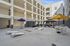 Modern apartment complex courtyard with stylish outdoor seating, vibrant umbrellas, and recreational cornhole setup, perfect for relaxation and socializing.