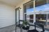 Charming outdoor nook featuring two stylish black chairs and a small table with a potted plant, perfect for a cozy retreat.