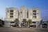 Contemporary apartment complex with spacious balconies and a stylish facade, enhanced by lush palm trees and clear blue skies.