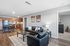 Modern open-concept living area with sleek black leather furniture, warm-toned kitchen, and cozy bedroom entrance.