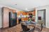 Chic kitchen with warm wooden cabinetry, sleek black appliances, and a cozy dining area featuring modern decor.