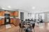 Bright and inviting open-concept living space featuring modern kitchen with wooden cabinetry, cozy dining area, and sunlit lounge with large windows.
