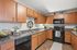 Modern kitchen with elegant wooden cabinetry, sleek black appliances, and stylish countertops. Cozy ambiance with decorative plants and charming accents.