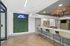 Modern communal space featuring stylish bar seating, sleek white counter, and chic wall art, enhanced by a vibrant green wall with neon signage.
