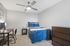 Cozy modern bedroom with stylish blue bedding, sleek wooden furniture, and a contemporary ceiling fan, perfect for relaxation.