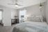 Inviting bedroom with soft natural light, cozy bedding, modern ceiling fan, and stylish decor, perfect for relaxation.