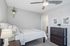 Serene bedroom with cozy bed and stylish decor, featuring a ceiling fan and modern furniture in a bright, inviting space.