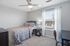 Cozy bedroom featuring a comfortable bed with colorful floral bedding, a modern ceiling fan, and a bright window with sheer curtains.