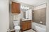 Elegant bathroom showcasing stylish wooden cabinetry, modern fixtures, and a pristine tile surround bathtub.