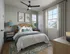 Charming bedroom with natural light, featuring elegant decor, stylish art, and cozy wicker headboard.