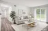 Inviting living room with chic decor, featuring a plush gray sofa, stylish coffee table, and vibrant indoor plant, enhanced by natural light from expansive sliding glass doors.