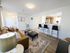 Bright and inviting living space with modern decor, cozy seating area, stylish bar stools, and open kitchen layout.