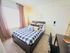 Inviting bedroom with cozy bedding, natural light, chic decor, and a functional workspace.